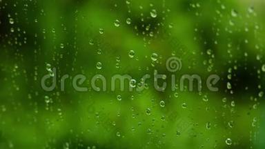 窗玻璃特写上的雨点。 一个夏天，雨水顺着玻璃流下来。 绿色背景4K